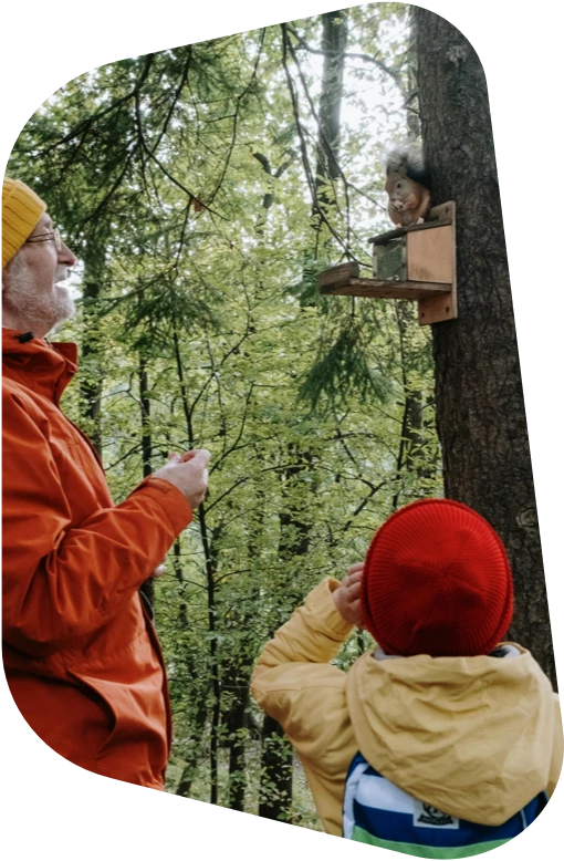 Hombre y niño estudiando un comedero de ardilla. pexels-cottonbro-6034405